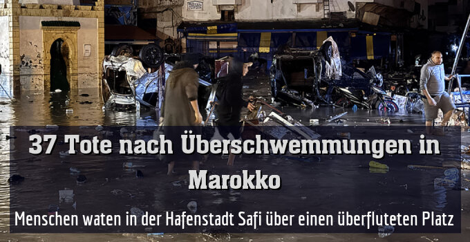 Menschen waten in der Hafenstadt Safi über einen überfluteten Platz