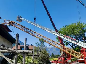 Kran kippt in Lana auf Häuserdach