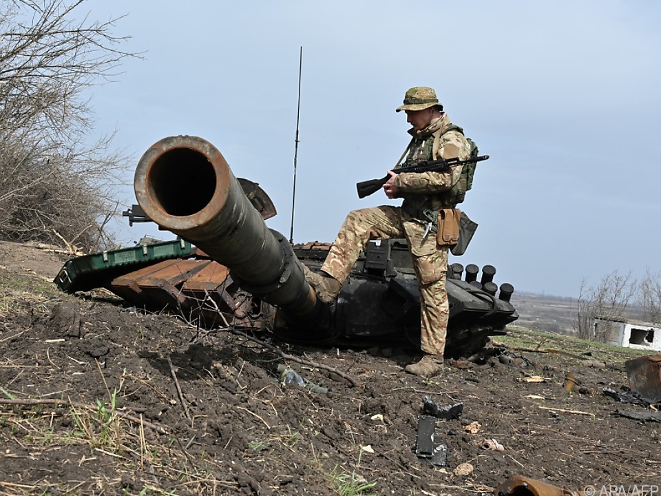 Ukrainischer Soldat betrachtet russisches Panzerwrack