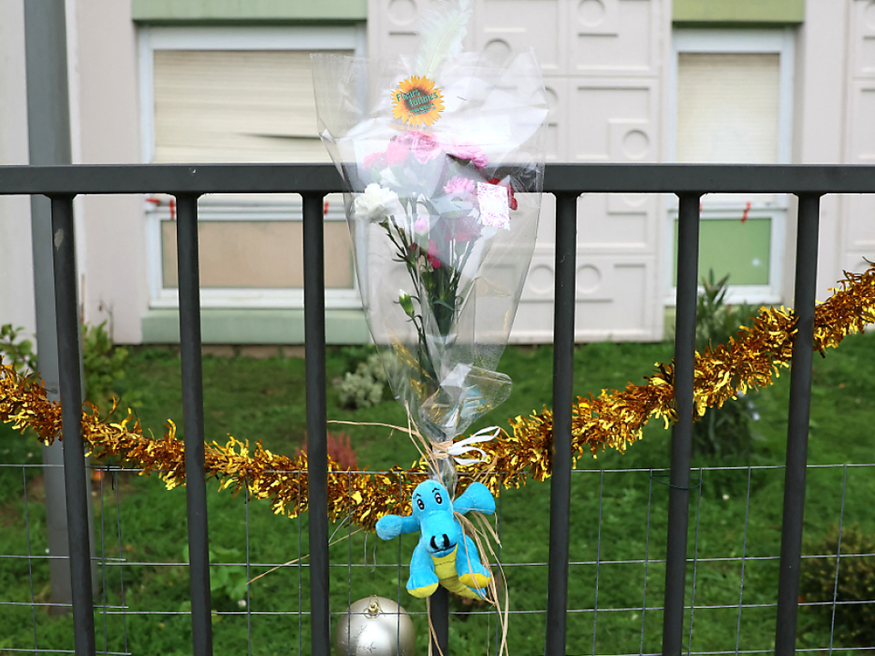 Blumen am Zaun vor Fundort von fünf Toten